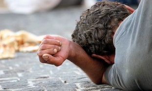 A homeless man lies on a sidewalk