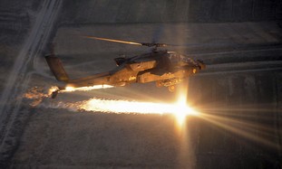 An AH-64D Apache attack helicopter fires flares.