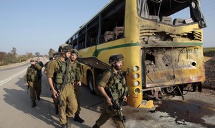 Soldiers walk past the damaged bus on April 7.