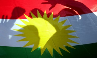 Kurds pose behind Kurdish flag