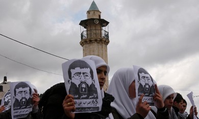 Palestinian students hold signs of Khader Adnan