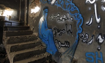 Encased in head-to-toe burka, image depicts distraught woman on cement stairwell, chronicles violence