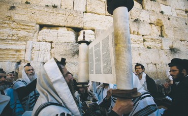 A worshiper holds up a Torah scroll
