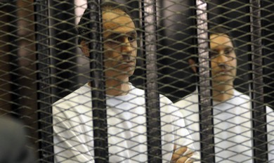 Gamal (L) and Alaa Mubarak, sons of former Egyptian President Hosni Mubarak, stand inside a cage at a courtroom in Cairo (Reuters)