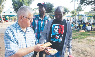 A VOLUNTEER hands out food to African migrants