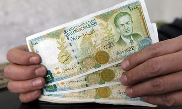 A money changer displays Syrian pounds