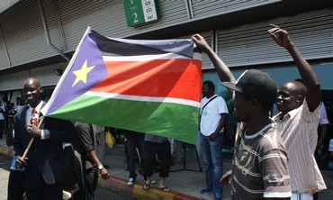 Migrants dance with South Sudanese flag