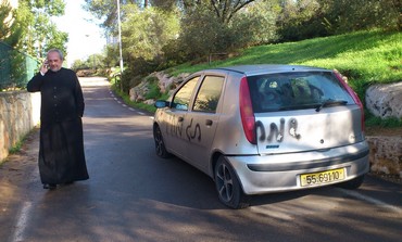 Father Claudio near spray-painted car