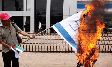 Protester burns Israeli flag with swastika on it in El Salvador