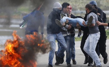 Stone-throwing Palestinian protesters carry a protester injured by IDF outside Ofer Prison, Feb 15  