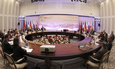 Participants sit at a table during talks on Iran's nuclear program in Almaty 