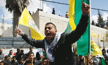 A Palestinian shouts as he holds a Fatah flag at the funeral of terrorist Maissara Abu Hamdiyeh.