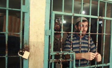 A Palestinian inmate stands behind the bars of a Hamas-run jail in Gaza City, July 23, 2012. 