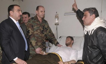 Syrian government officials and military personnel visit a victim of chemical weapons.