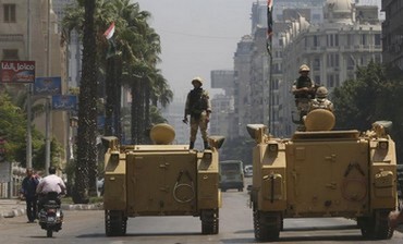 A soldier holds his weapon as he stands on an APC in Cairo, August 16, 2013.