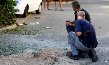 Israeli police survey damage to a village near Nahariya following Thursday's rocket attack.