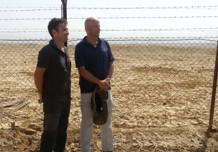 Michael Heinman (left) and Ronen Shimon stand behind a fence marking off mines at Qasr el-Yahud (photo credit: JUDITH SUDILOVSKY)