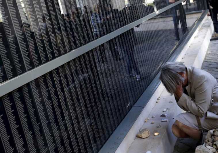 A woman prays in front of a wall bearing the names of Holocaust victims in Budapest