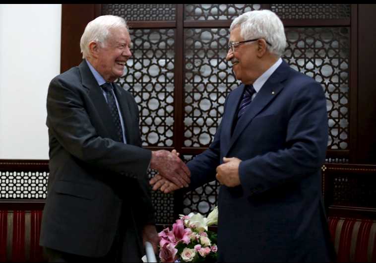 Palestinian President Mahmoud Abbas (R) shakes hands with former US president Jimmy Carter
