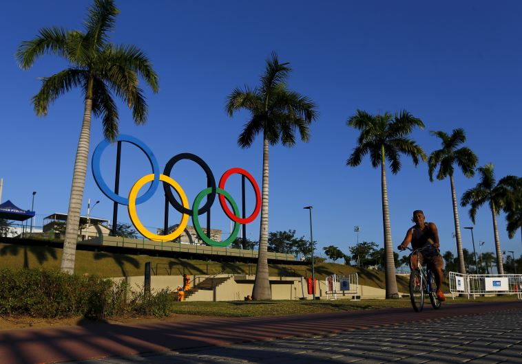 A man exercises next to the Olympic rings placed at the Madureira Park ahead the Rio 2016 Olympics 