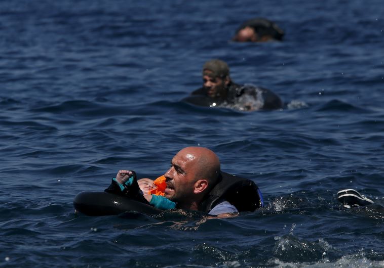 A Syrian refugee holding a baby in a lifetube swims towards the shore after their dinghy deflated 