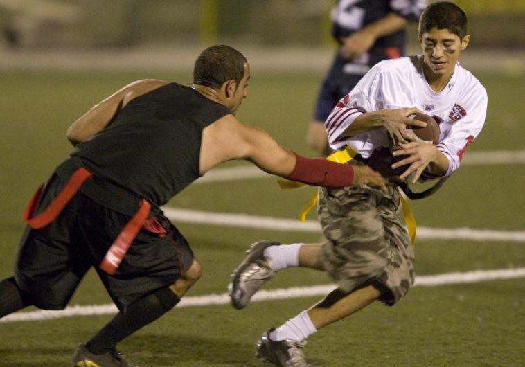 Amirhossein Sahiholnasab (R) tries to evade a tackle during the Tehran Titans flag football game