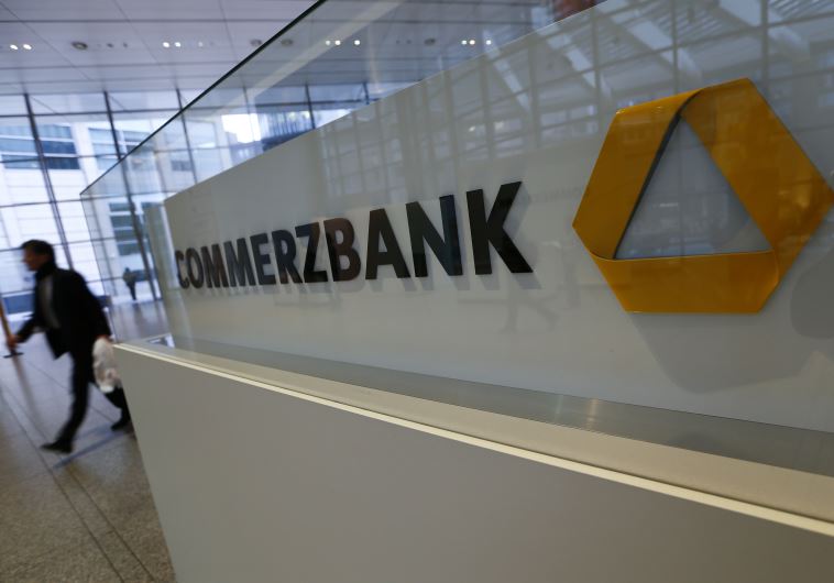 A man walks past a logo of Commerzbank