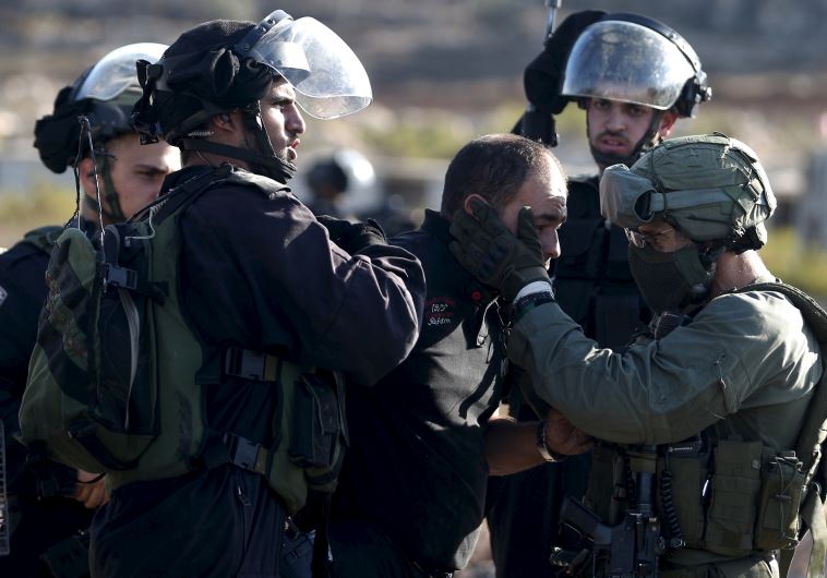 Israeli policemen detain a Palestinian protester during clashes near the Jewish settlement of Beit E