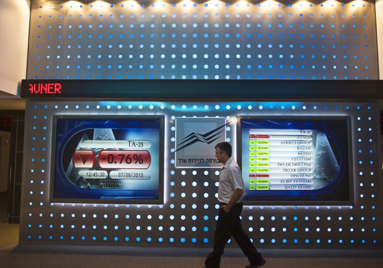 An employee walks past a screen displaying market data at the Tel Aviv Stock Exchange