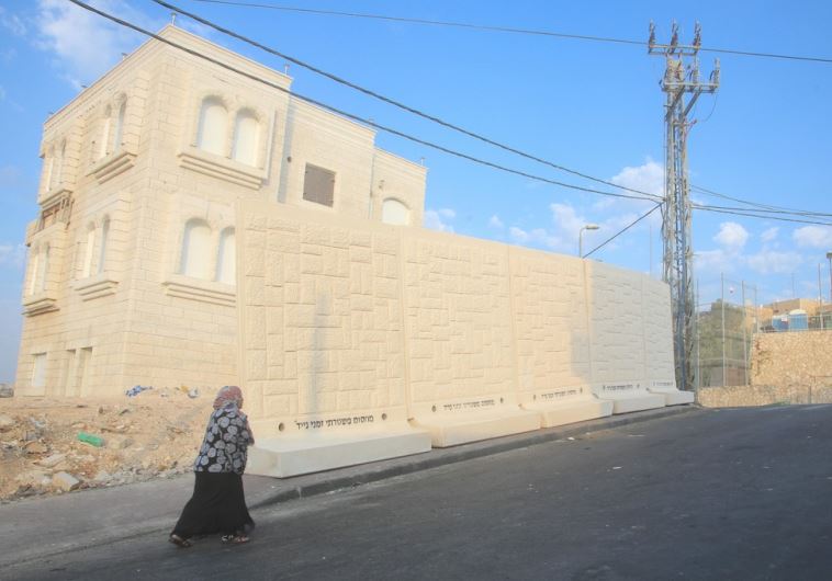 A Palestinian from the east Jerusalem neighborhood of Jebl Mukaber walks past a barrier