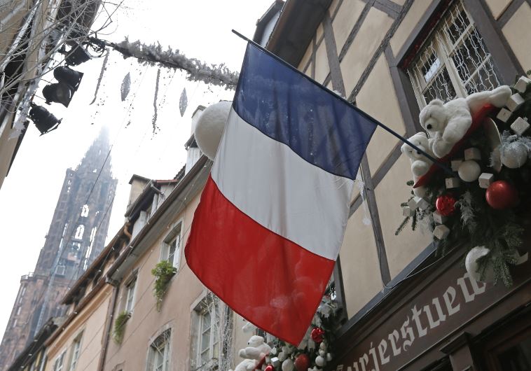 A French flag hangs from a window of a restaurant decorated for Christmas holiday season