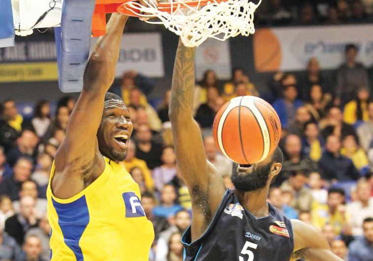 Maccabi Tel Aviv forward Trevor Mbakwe (left) dunks over Hapoel Eilat’s C.J. Leslie