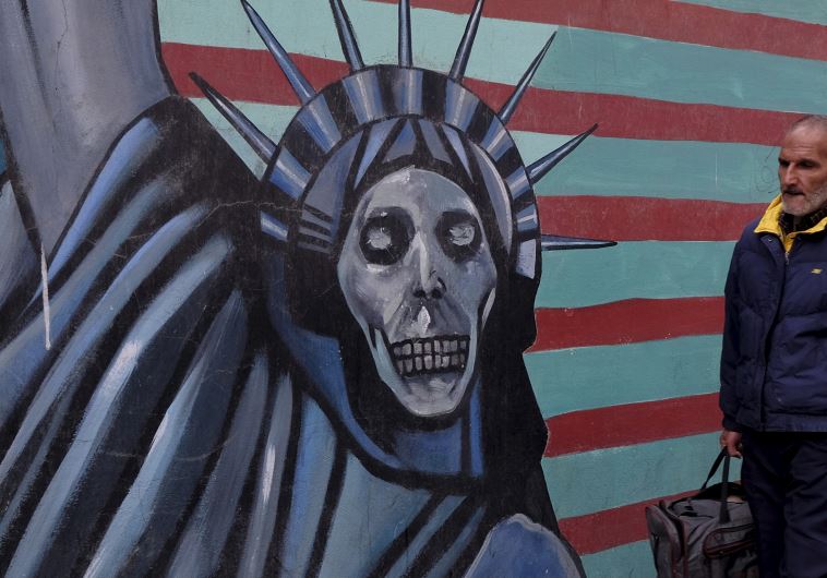An Iranian man walks past a mural on the wall of former US embassy in Tehran