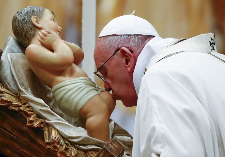Pope Francis kisses a statue of baby Jesus as he leads the Christmas night Mass