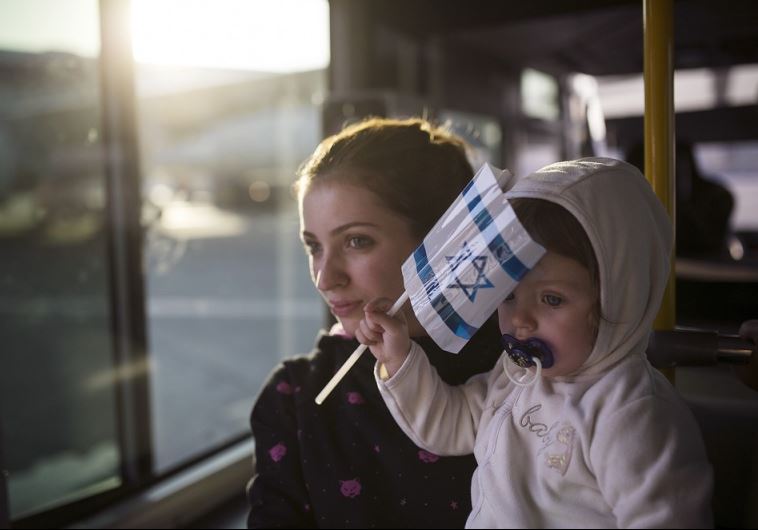 A Jewish immigrant from Ukraine holds her daughter aboard a bus