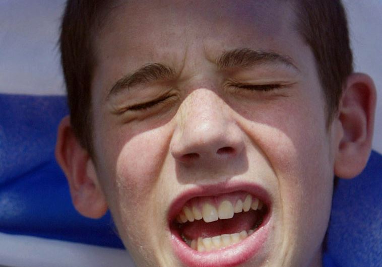 A boy sings underneath the Israeli flag at the Israel Solidarity Rally in London