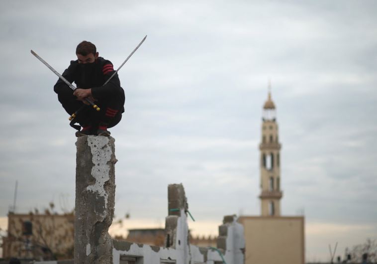 A Palestinian youth holds swords as he demonstrates his ninja-style skills for a photographer 