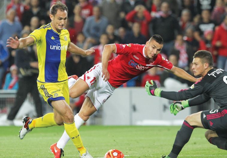 Hapoel Beersheba midfielder Ovidiu Hoban (center) scores past Maccabi Tel Aviv goalkeeper Predrag Ra