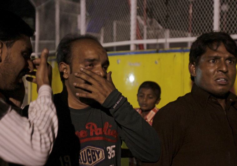 Men mourn the death of their relatives after a blast outside a public park in Lahore, Pakistan