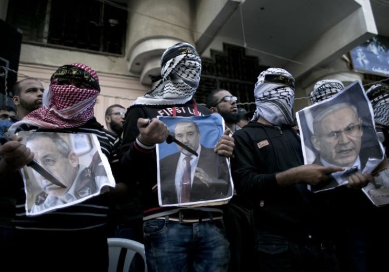 Palestinians hold knives in front of posters of Netanyahu (R), Liberman, and Barak