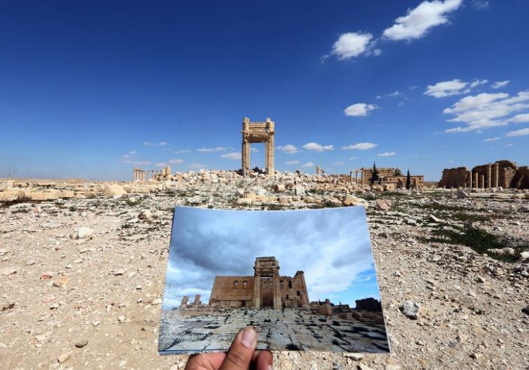 A general view taken on March 31, 2016 shows a photographer holding picture of the Temple of Bel