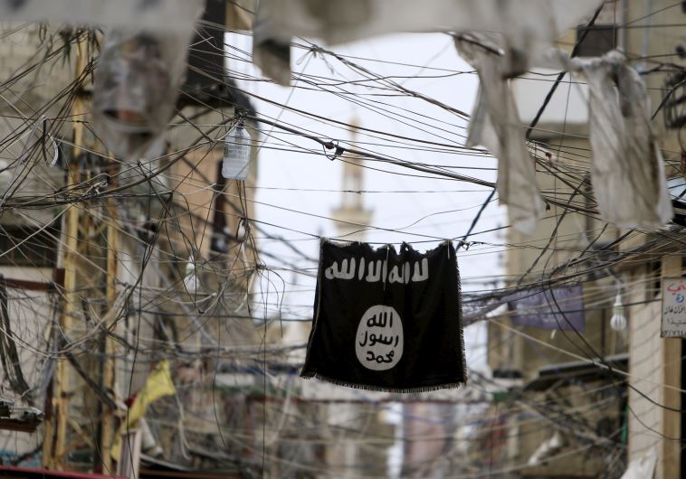 An Islamic State flag hangs amid electric wires over a street