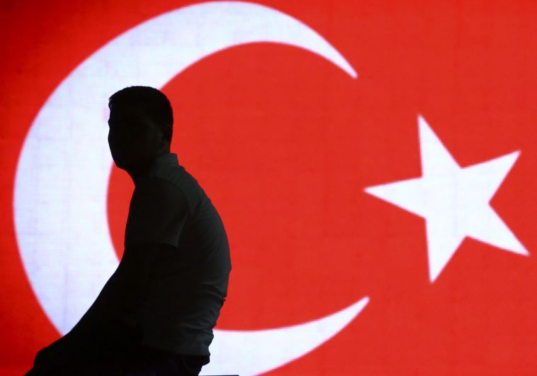 Man sits in front of Turkish flag 