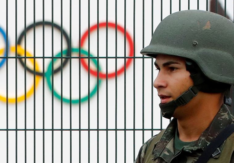 A Brazilian military police soldier patrols at the security fence outside the 2016 Rio Olympics Park
