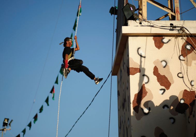 SUMMER FUN in Gaza. A Palestinian rappels down from a building during a Hamas-run summer camp that b
