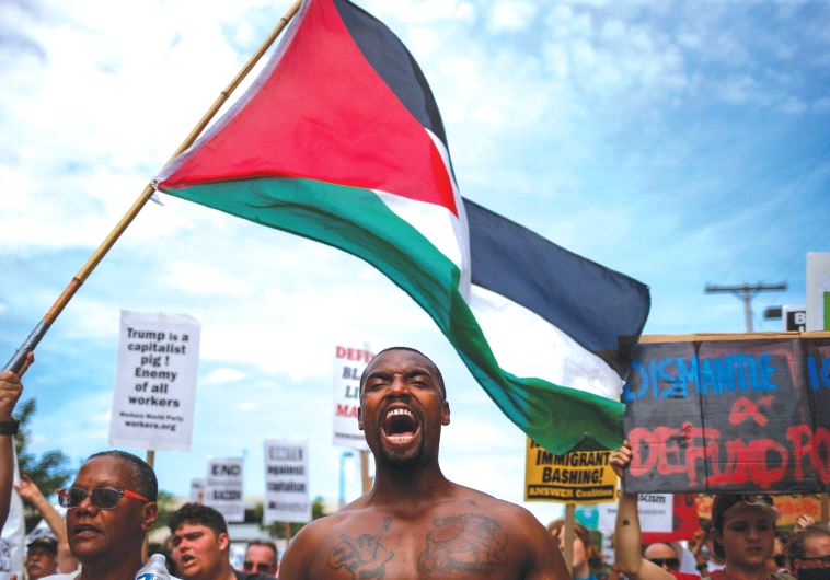 DEMONSTRATORS WAVE the Palestinian flag during a march by various groups, including Black Lives Matt