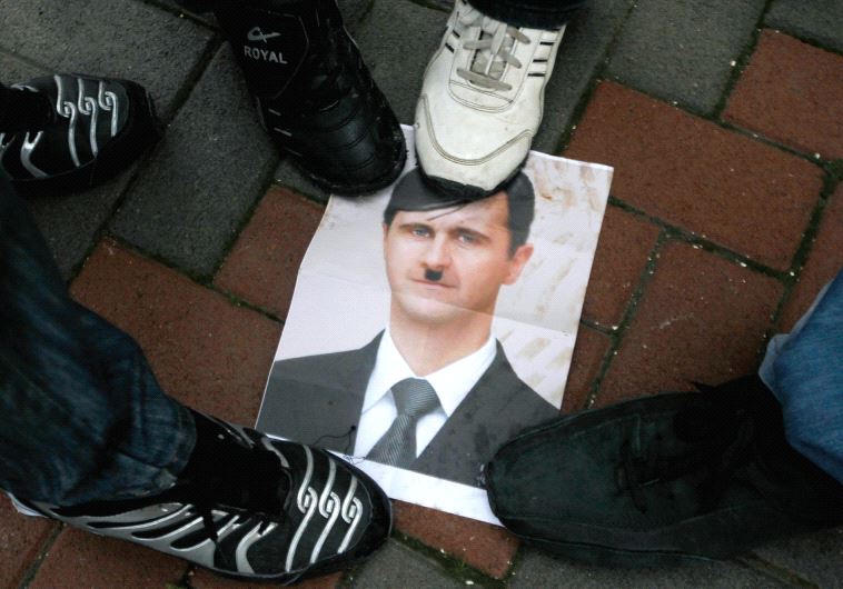 PROTESTERS STEP on a picture depicting Syria’s President Bashar al-Assad as Hitler during a protest 