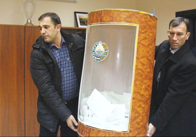 MEMBERS OF a local electoral commission carry a ballot box after the presidential election in Tashke