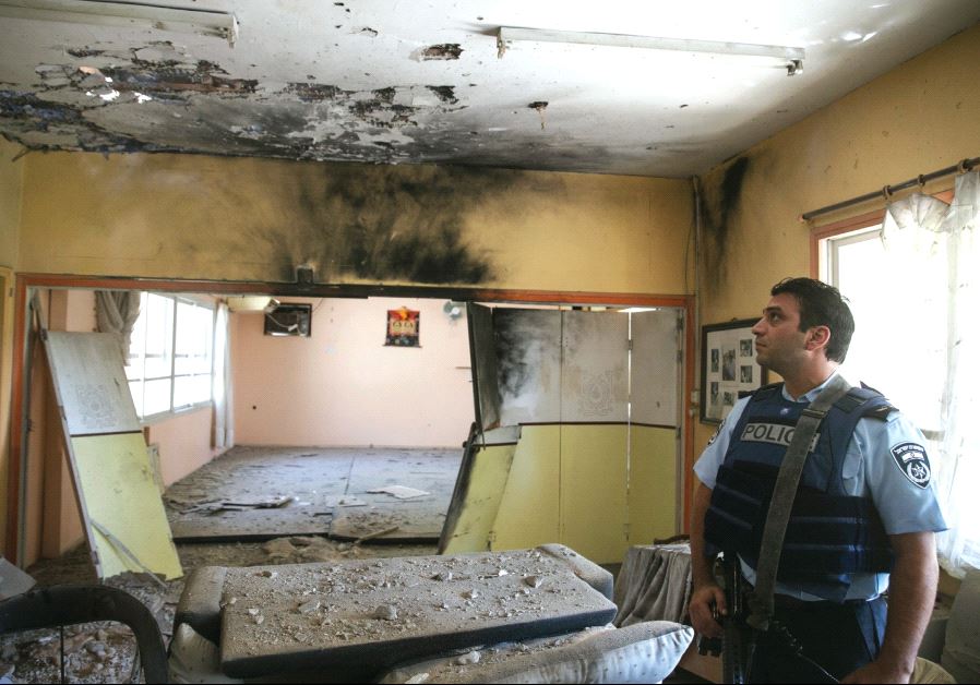 A POLICEMAN surveys a building damaged from a Palestinian mortar.