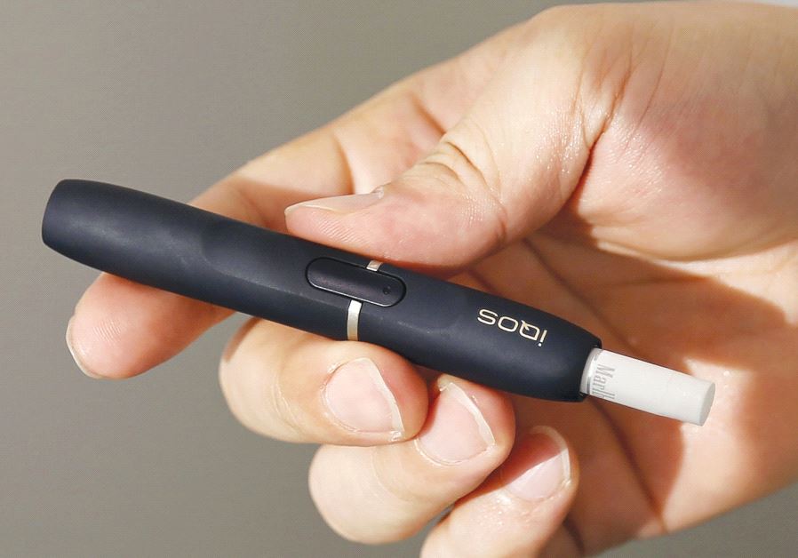 A CUSTOMER holds a Philip Morris iQOS e-cigarette at an iQOS store in Tokyo last year